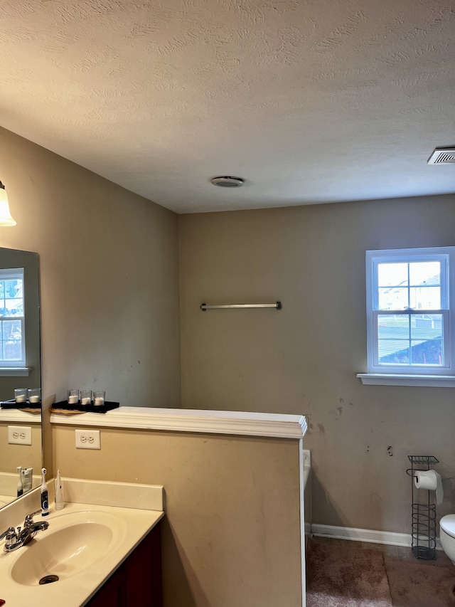 bathroom featuring toilet, a textured ceiling, and vanity