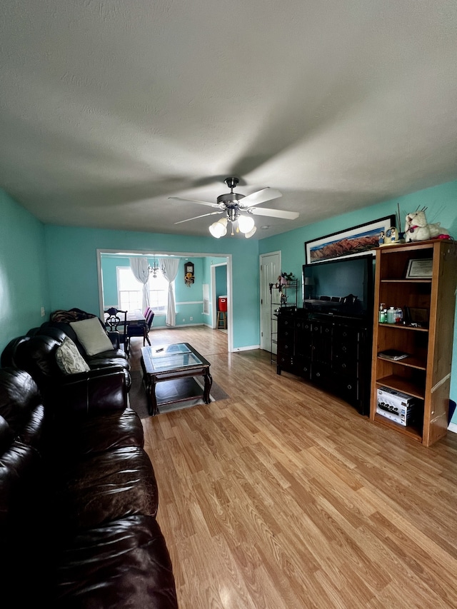 living room featuring a textured ceiling, ceiling fan, and light wood-type flooring