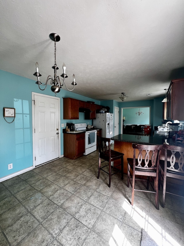 kitchen featuring tile patterned flooring, hanging light fixtures, a textured ceiling, an inviting chandelier, and white appliances