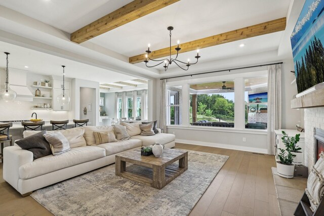 living room featuring a fireplace, beam ceiling, a chandelier, and hardwood / wood-style flooring