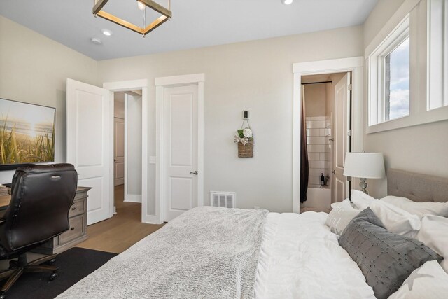 bedroom featuring ensuite bath and wood-type flooring