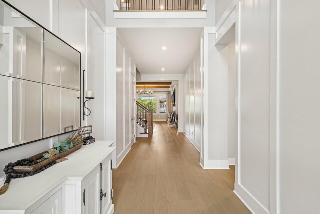 corridor featuring light wood-type flooring and a towering ceiling