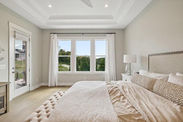 bedroom featuring a tray ceiling, light hardwood / wood-style flooring, ceiling fan, and access to outside