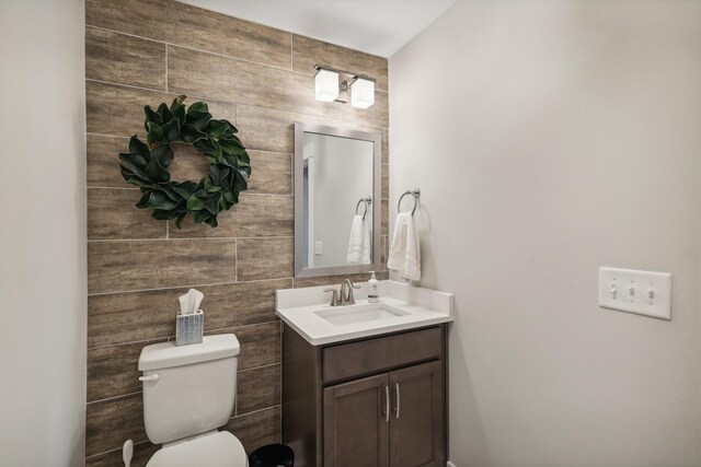 bathroom with tile walls, toilet, and vanity