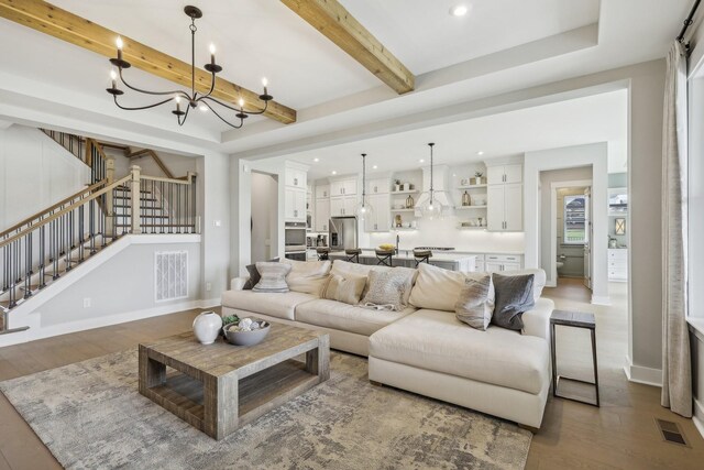 living room featuring beam ceiling, a notable chandelier, and wood-type flooring