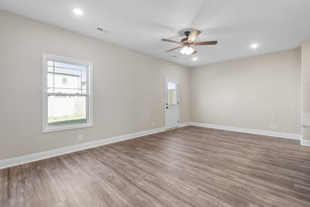 spare room with baseboards, visible vents, and wood finished floors