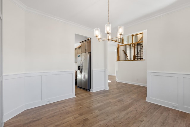 unfurnished dining area featuring a chandelier, dark hardwood / wood-style floors, and ornamental molding