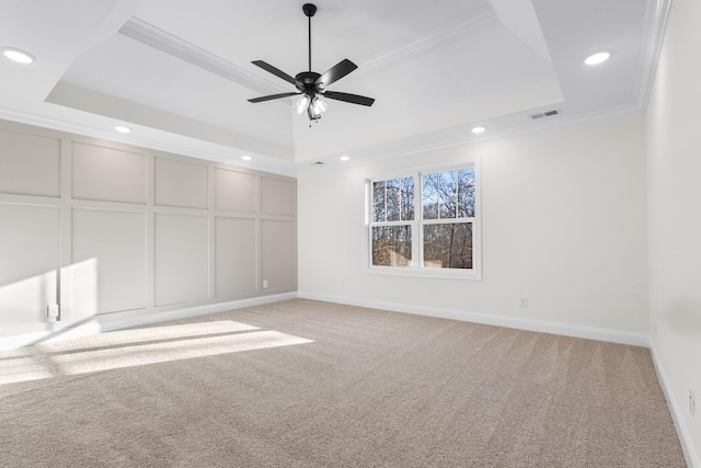 unfurnished room with ornamental molding, light carpet, and a tray ceiling