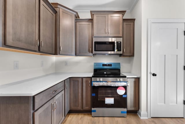 kitchen featuring light wood-type flooring, dark brown cabinetry, and appliances with stainless steel finishes