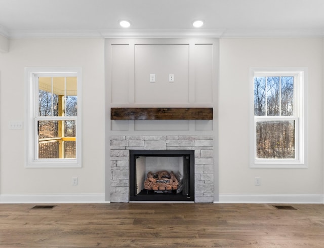 unfurnished living room with hardwood / wood-style flooring, a stone fireplace, and ornamental molding