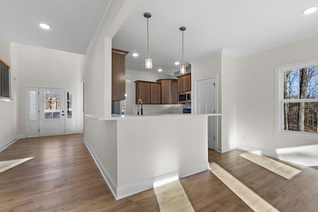 kitchen featuring decorative light fixtures, ornamental molding, dark wood-type flooring, and a wealth of natural light