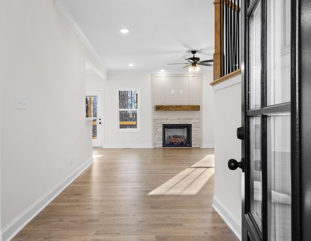 unfurnished living room with a fireplace, light hardwood / wood-style flooring, ceiling fan, and crown molding