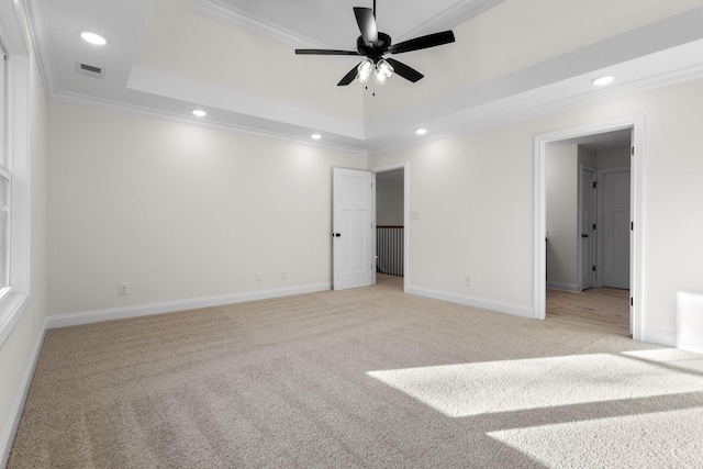 carpeted spare room featuring a tray ceiling, ceiling fan, and crown molding