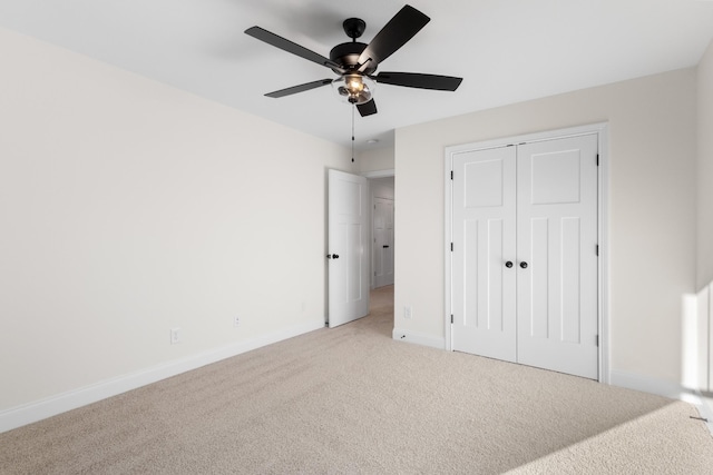 unfurnished bedroom featuring ceiling fan, a closet, and light carpet