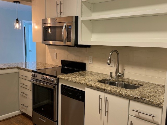 kitchen featuring sink, appliances with stainless steel finishes, dark wood-type flooring, tasteful backsplash, and pendant lighting