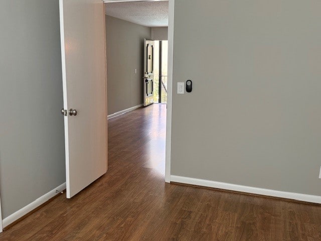 corridor with hardwood / wood-style flooring and a textured ceiling