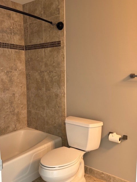 bathroom with tile patterned flooring, tiled shower / bath combo, and toilet