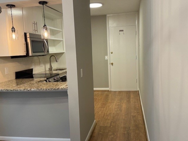 kitchen featuring backsplash, hardwood / wood-style floors, sink, range, and pendant lighting