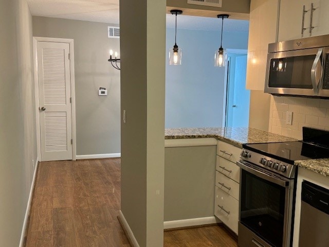 kitchen with stainless steel appliances, tasteful backsplash, light stone countertops, dark hardwood / wood-style flooring, and hanging light fixtures