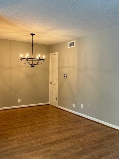 unfurnished room featuring hardwood / wood-style flooring, a notable chandelier, and a textured ceiling