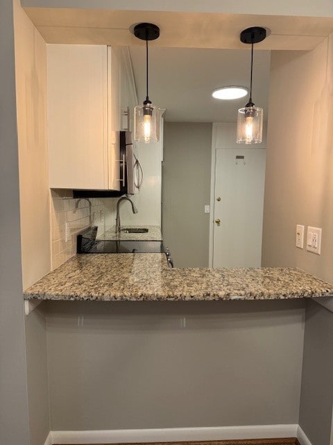 kitchen with tasteful backsplash, kitchen peninsula, and hanging light fixtures