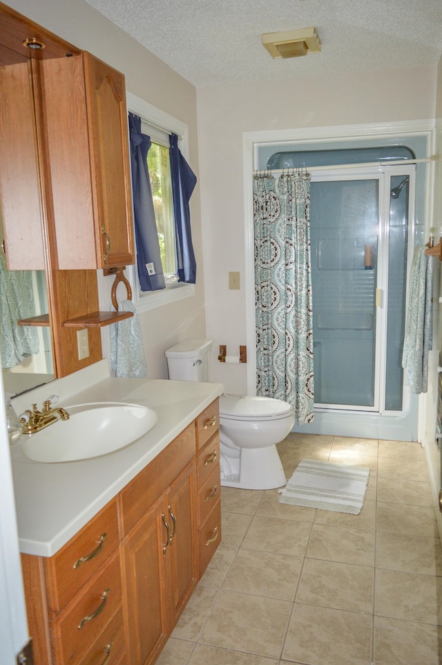 bathroom with a shower with shower curtain, vanity, tile patterned floors, a textured ceiling, and toilet