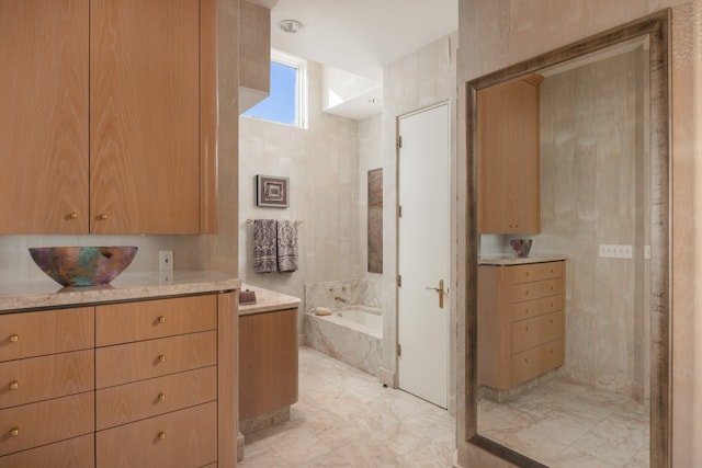 bathroom featuring tiled bath, tile patterned flooring, and vanity