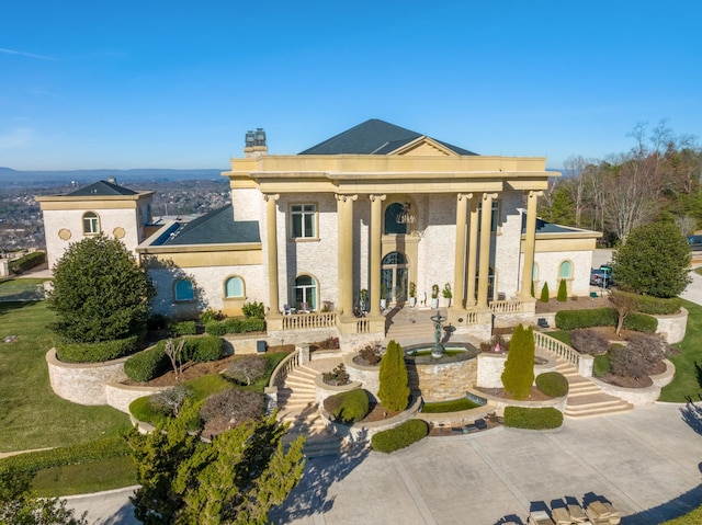 neoclassical home featuring a patio, a chimney, and stairs