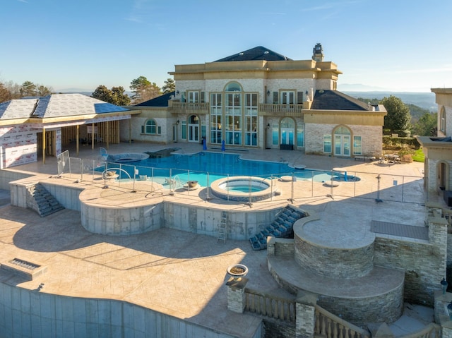 outdoor pool with an in ground hot tub, french doors, and a patio area