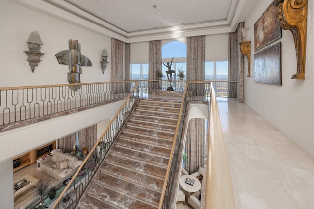 corridor featuring tile patterned flooring, a raised ceiling, and ornamental molding