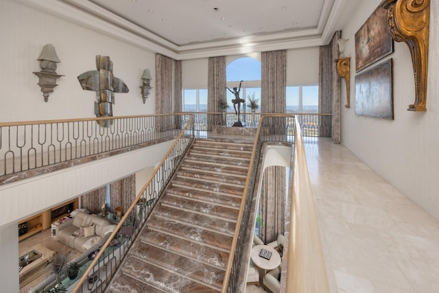 stairs featuring a raised ceiling and crown molding