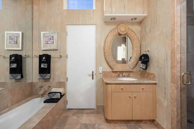 bathroom with tile patterned flooring, tiled tub, and vanity