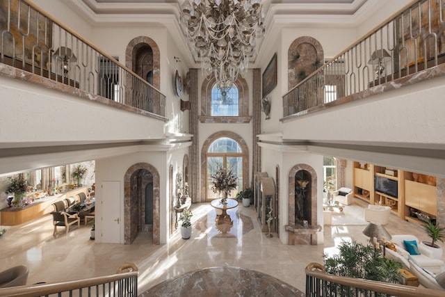 tiled foyer with a towering ceiling, ornamental molding, and a chandelier