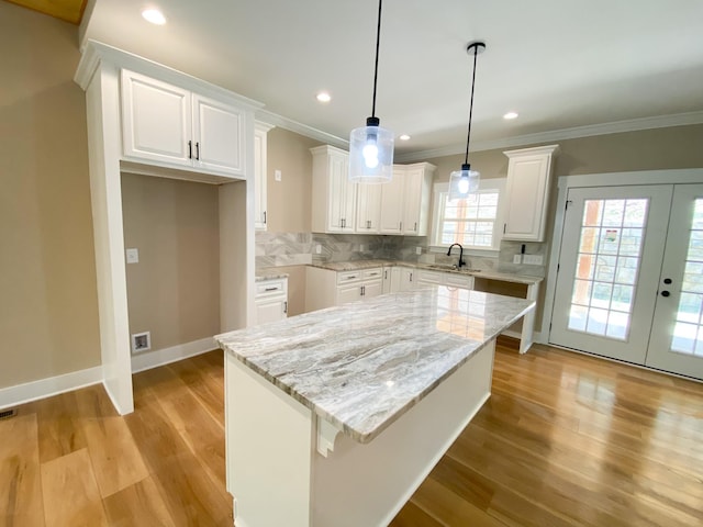 kitchen featuring white cabinets, a sink, and a center island