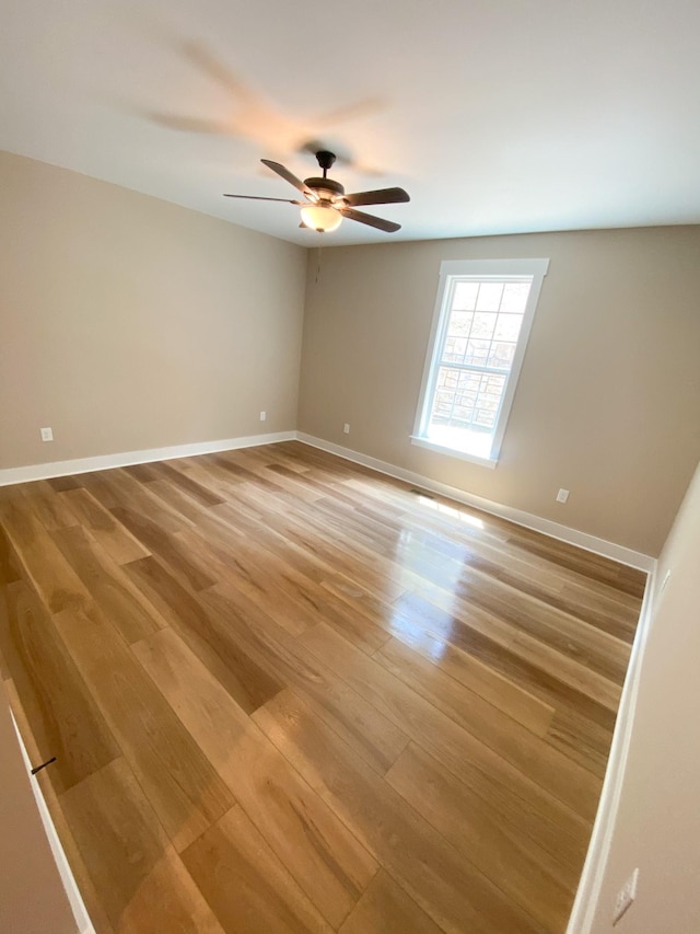 spare room featuring light wood-style flooring, baseboards, and ceiling fan