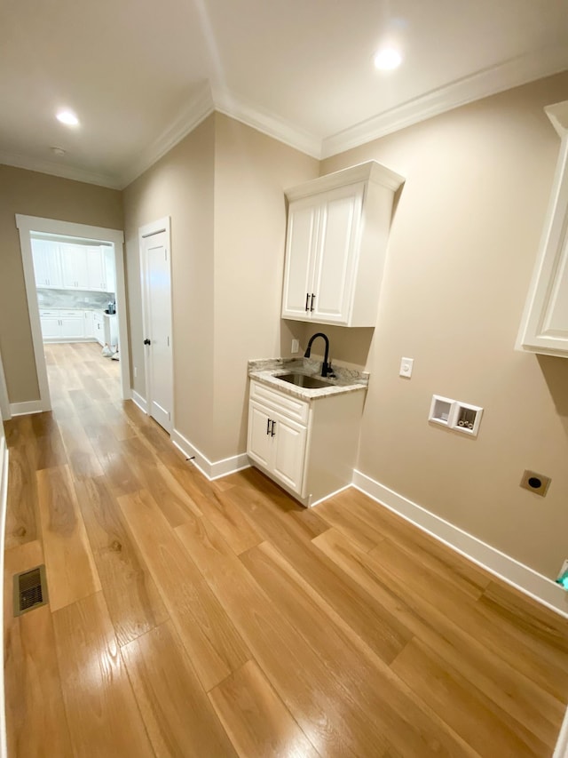 interior space featuring a sink, crown molding, light wood-type flooring, washer hookup, and electric dryer hookup