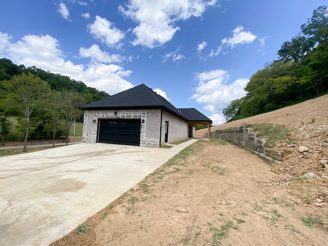 view of home's exterior featuring concrete driveway, brick siding, and an attached garage