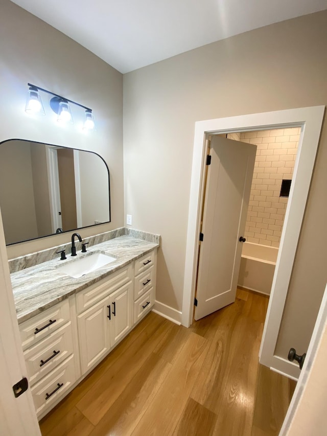 full bathroom with baseboards, a washtub, wood finished floors, and vanity