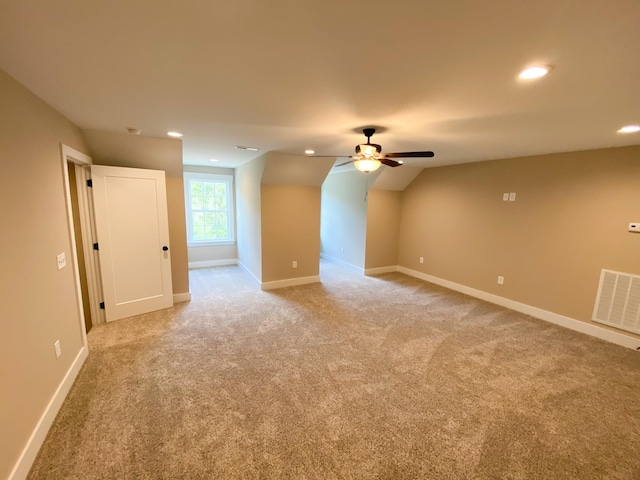 additional living space featuring light carpet, visible vents, and baseboards