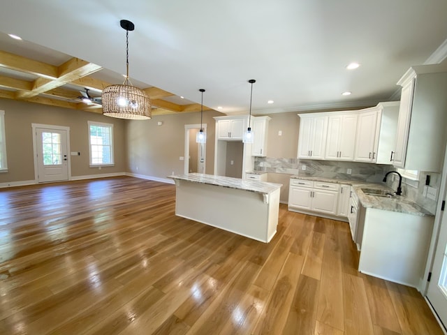 kitchen featuring a center island, backsplash, open floor plan, white cabinetry, and a sink