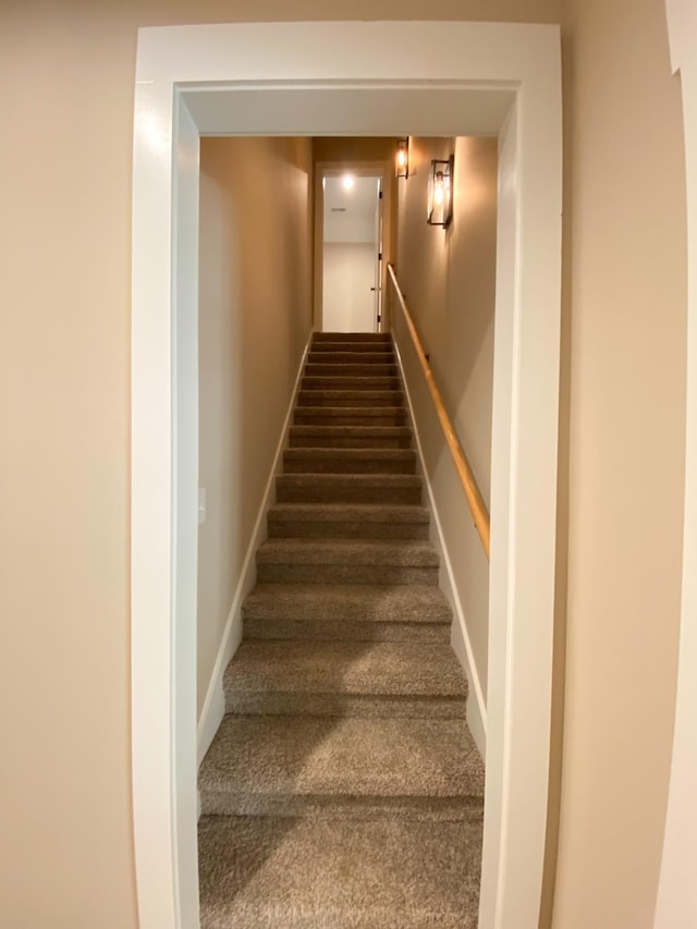 stairway with baseboards and carpet flooring