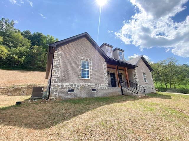 exterior space with brick siding, crawl space, central AC unit, and a front yard