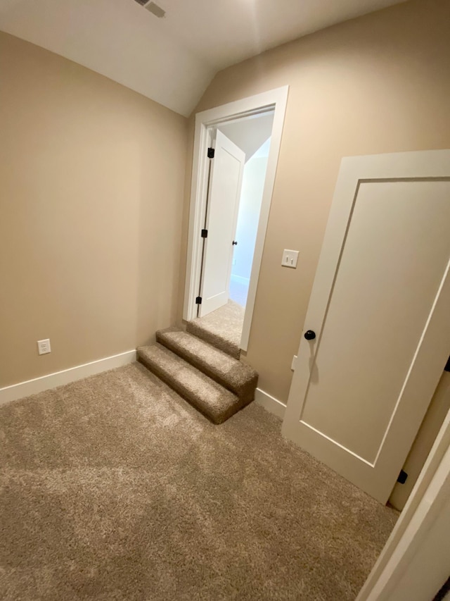 interior space featuring vaulted ceiling, carpet floors, and baseboards