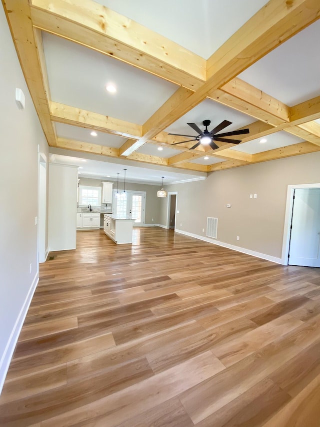 unfurnished living room with light wood finished floors, visible vents, baseboards, a ceiling fan, and beamed ceiling