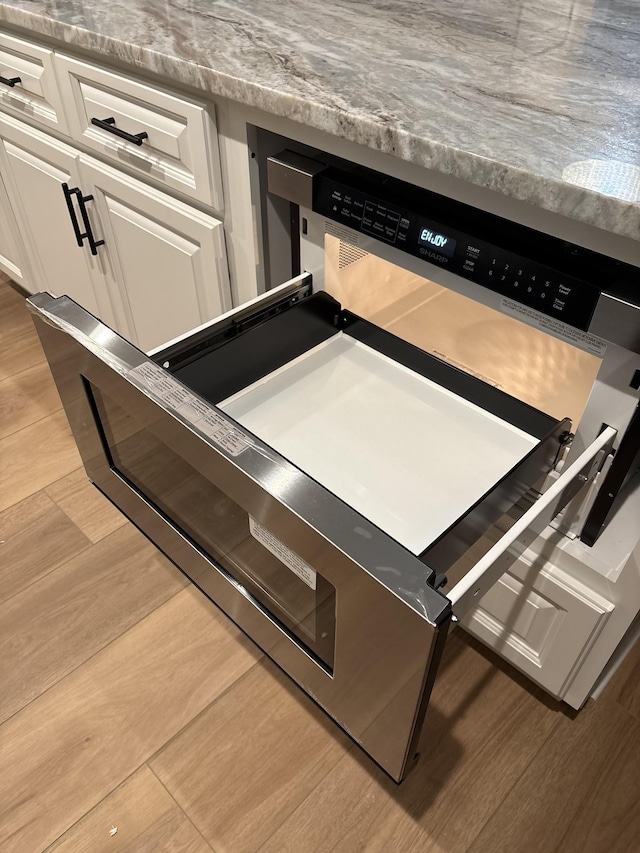 room details featuring light wood-style floors, light countertops, and white cabinetry