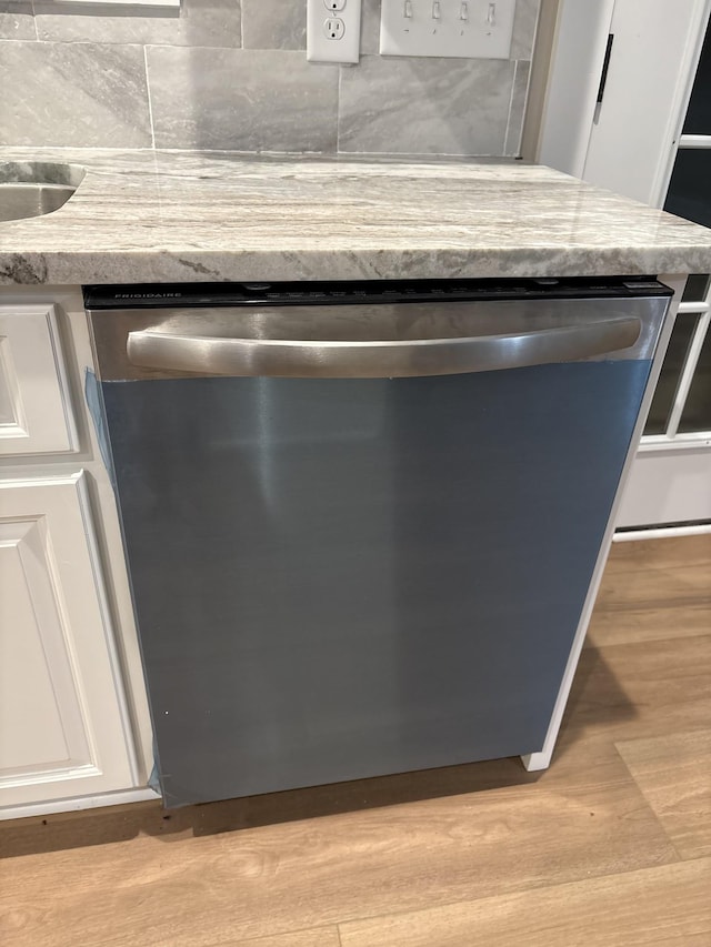 details with light countertops, stainless steel dishwasher, light wood-type flooring, and white cabinets