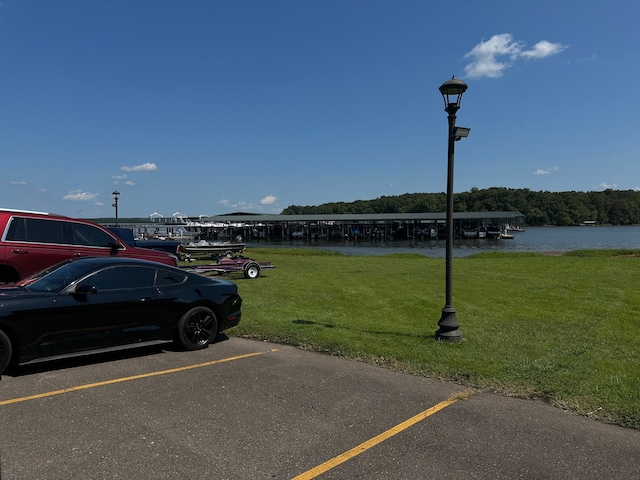 view of parking / parking lot with a water view and a yard