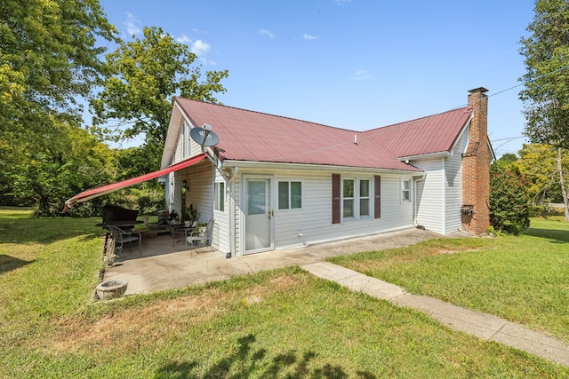 exterior space with a front yard, a patio area, metal roof, and a chimney