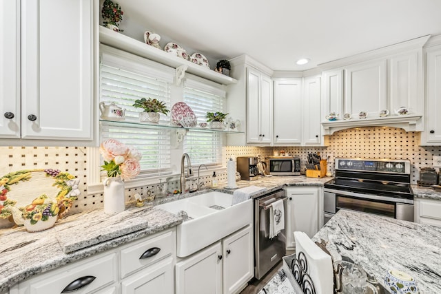 kitchen featuring white cabinets, light stone countertops, stainless steel appliances, and a sink