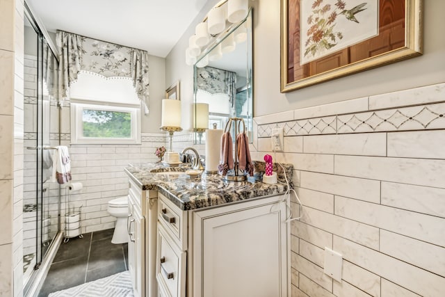 bathroom featuring a shower with shower door, tile patterned floors, vanity, tile walls, and toilet